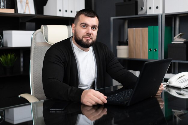 Retrato de hombre joven con laptop en la oficina de negocios