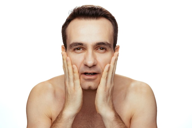 Foto retrato de un hombre joven con una limpieza perfecta de la piel afeitada posando aislada sobre el fondo blanco del estudio