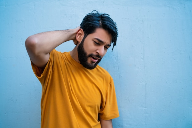 Retrato de hombre joven con la mano en el cuello con dolor de cuello. Concepto de salud.