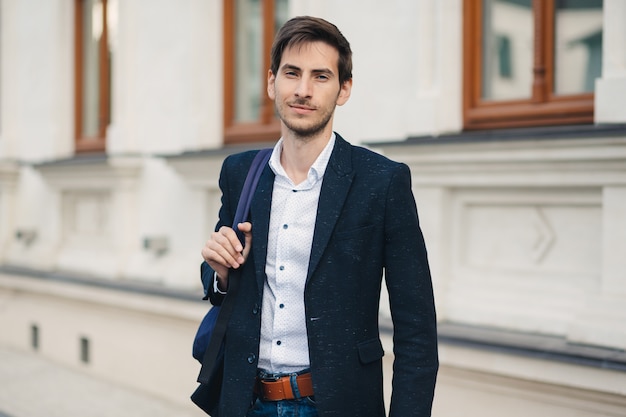 Retrato de hombre joven con mochila en la ciudad