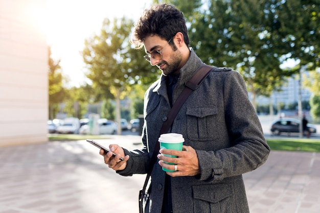 Retrato de hombre joven moderno con su teléfono móvil en la calle.