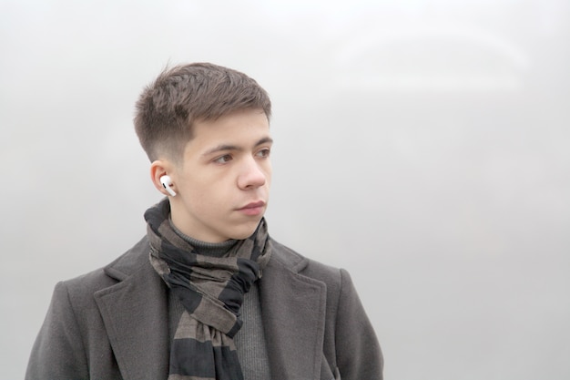 Foto retrato de un hombre joven en un paseo marítimo de la ciudad, el clima brumoso de invierno. foto en tonos grises