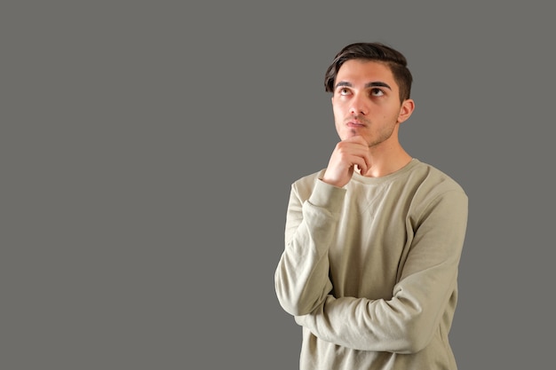 Retrato de hombre joven pensativo aislado sobre fondo gris