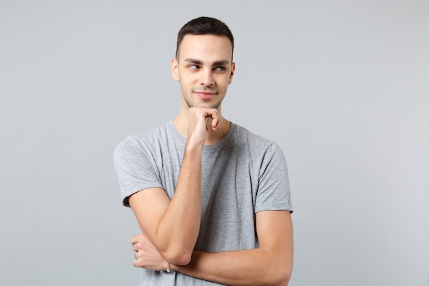 Retrato de hombre joven pensativo en ropa casual mirando a un lado y poner la mano apuntando hacia arriba en la barbilla