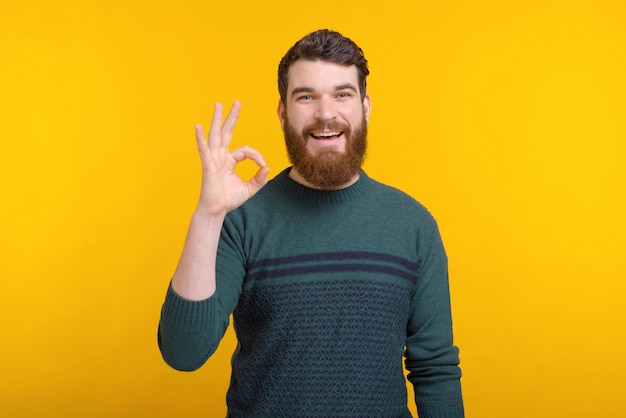 Retrato de un hombre joven que muestra gesto aceptable sobre fondo amarillo.