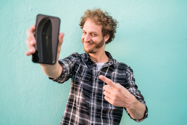 Retrato de hombre joven que muestra la pantalla del teléfono inteligente en blanco.