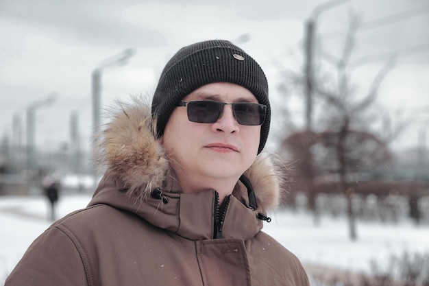 Retrato de hombre joven en ropa casual de invierno con gafas en la ciudad a pie