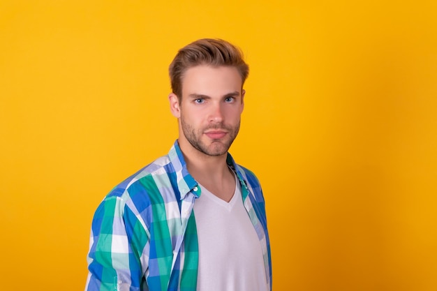 Retrato de hombre joven serio y guapo Hombre caucásico fondo amarillo Chico sin afeitar en camisa a cuadros Adulto masculino