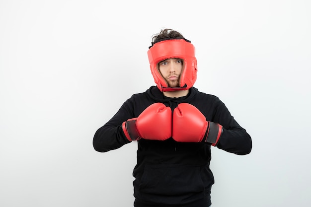 Foto retrato de hombre joven con sombrero de boxeo rojo de pie y posando.