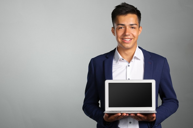 Retrato de hombre joven sonriente con laptop