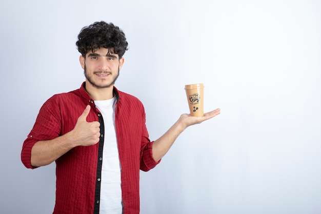 Retrato de hombre joven con taza de café de pie sobre fondo blanco. Foto de alta calidad