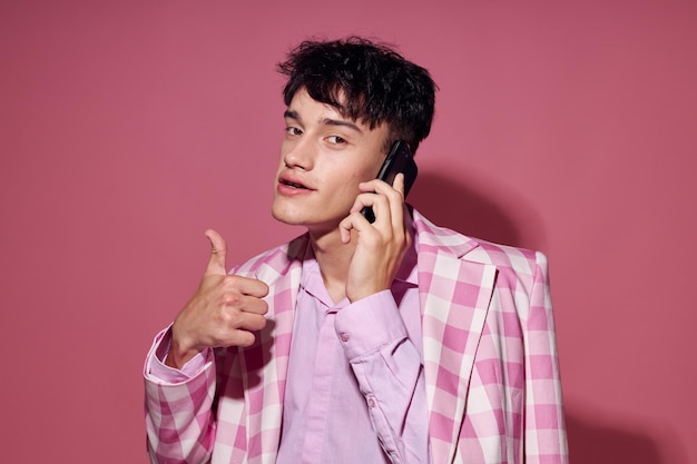 Retrato de un hombre joven con un teléfono en la mano chaqueta rosa moda estilo de vida elegante inalterado