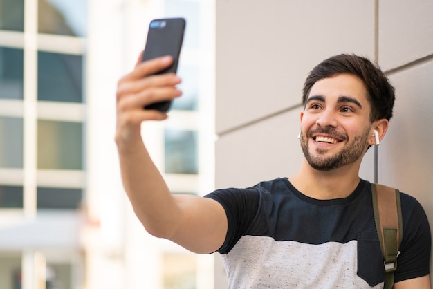 Retrato de hombre joven con una videollamada en el teléfono móvil mientras está de pie al aire libre