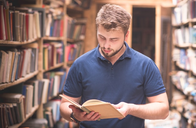 Retrato de un hombre leyendo un libro de pie en una vieja biblioteca pública