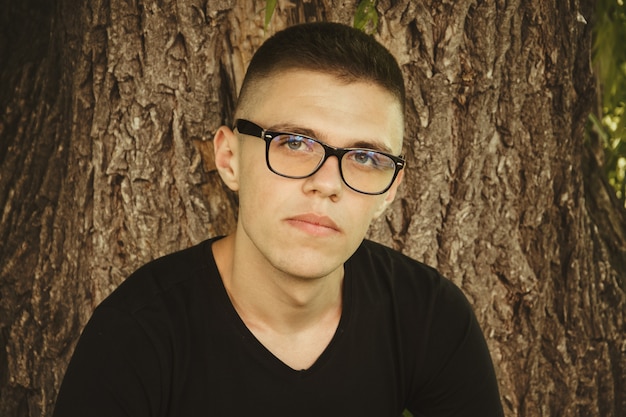 Retrato de hombre lindo joven y sonriente con gafas en el parque