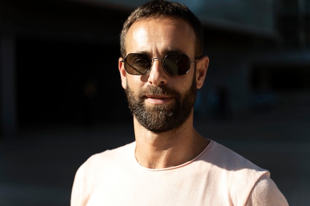 Retrato hombre macho latino barbudo con elegantes gafas de sol mirando a la cámara