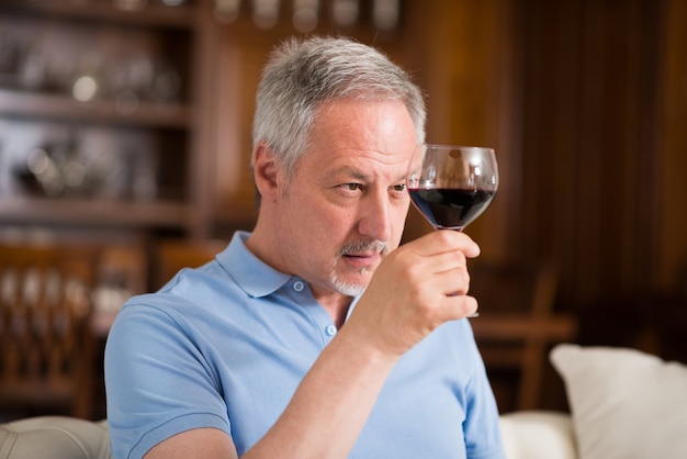 Foto retrato de un hombre maduro disfrutando de un vaso de vino tinto en casa
