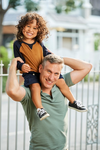 Retrato de hombre maduro feliz dando caballito a su hijo toddle cuando están jugando al aire libre