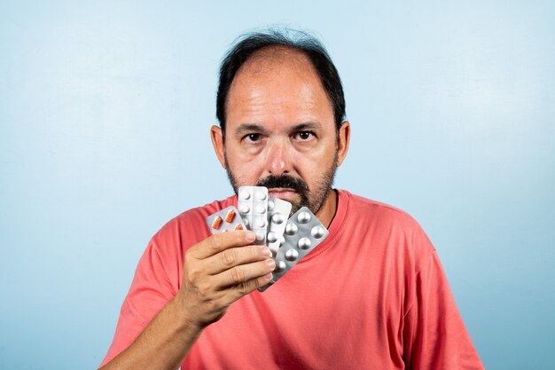 Retrato de hombre maduro de pie sobre la pared azul.