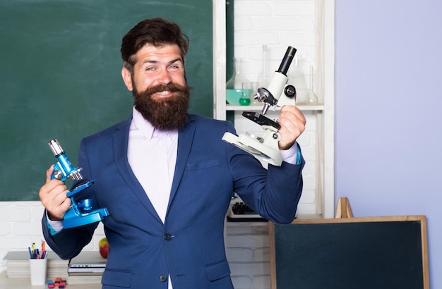 Retrato de hombre maestro emocionado asombrado con microscopio, profesor, tutor, mentor en el aula de la escuela.