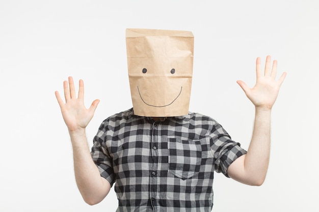Foto retrato de hombre en máscara de bolsa de papel feliz sobre fondo blanco.