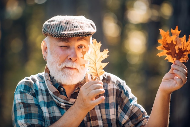 Retrato de hombre mayor en el parque de otoño Hoja de arce en la ruta de senderismo en el parque