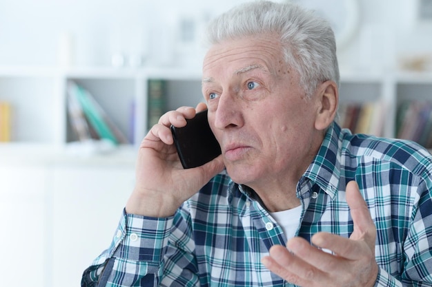 Retrato de un hombre mayor con teléfono en casa