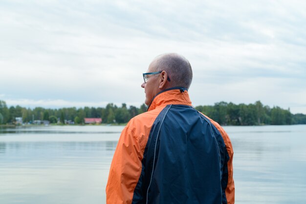 Retrato de hombre mayor en la tranquila vista del lago