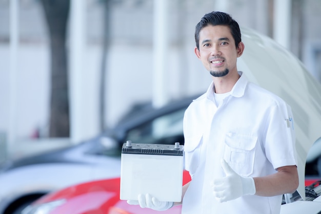 Retrato de hombre mecánico con batería de coche en taller