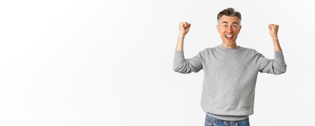 Retrato de un hombre de mediana edad emocionado y feliz celebrando la victoria o el éxito levantando las manos y diciendo