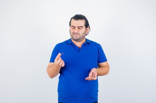 Retrato de hombre de mediana edad encendiendo fósforos en camiseta de polo y mirando pensativo vista frontal