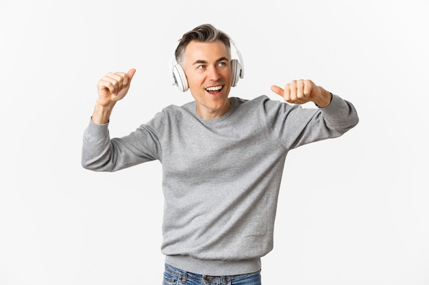 Retrato de hombre de mediana edad guapo y moderno, escuchando música en auriculares