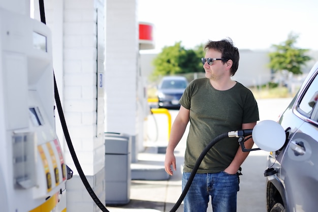 Retrato del hombre de mediana edad que llena el combustible de gasolina en coche