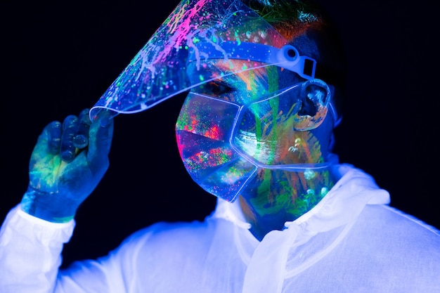 Foto retrato de hombre médico en ropa protectora en luz de neón ultravioleta