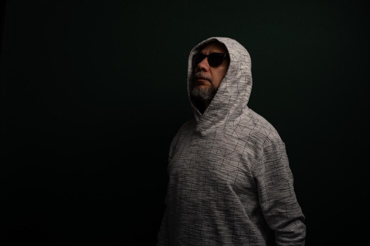 Foto retrato de un hombre misterioso con una sudadera con capucha de pie en silencio