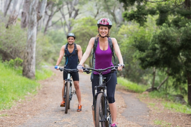 Retrato de hombre y mujer en bicicleta en el bosque