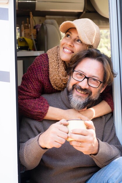 Retrato de hombre y mujer de edad madura sonriendo y divirtiéndose y felicidad sentados en la acogedora puerta de casa alternativa de la autocaravana Un par de turistas disfrutan juntos de actividades de ocio de vacaciones