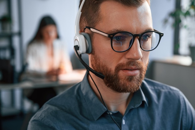 Retrato de hombre La mujer está en el fondo Dos empleados están trabajando juntos en la oficina moderna