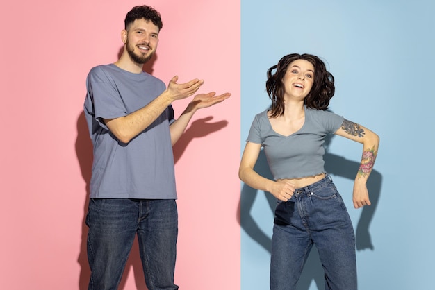 Retrato de hombre y mujer jóvenes posando alegremente alrededor de un fondo azul y rosa Juventud emotiva