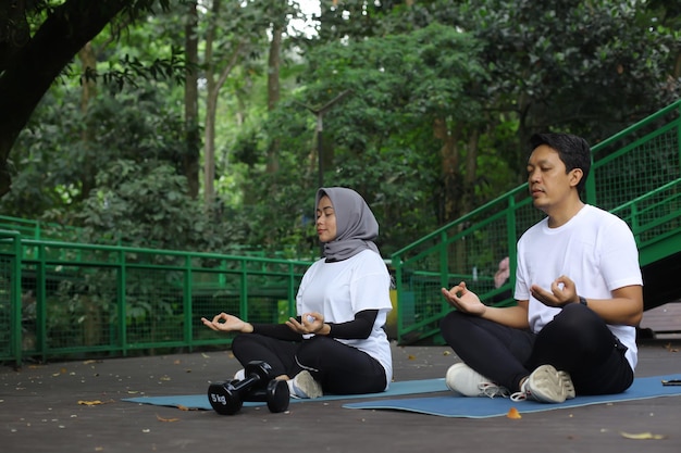Retrato de hombre y mujer musulmana meditando en pose de loto en estera de yoga. Par disfrutar incluso pacífica