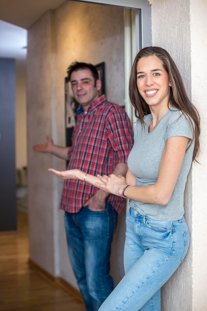 Foto retrato de un hombre y una mujer sonrientes gestando mientras están de pie en la puerta