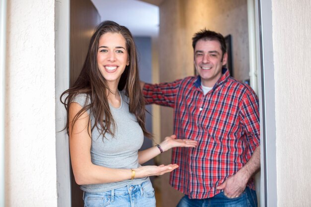 Foto retrato de un hombre y una mujer sonrientes gestando mientras están de pie en la puerta