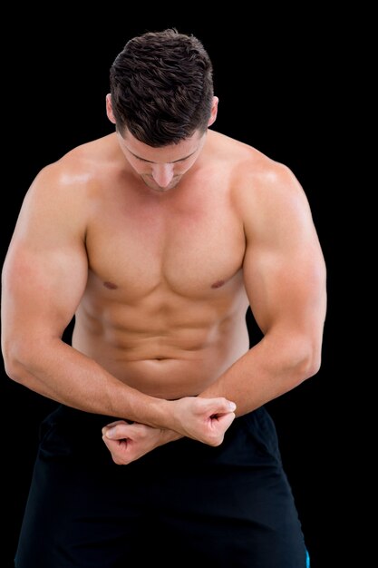 Retrato de un hombre musculoso sin camisa posando sobre fondo negro