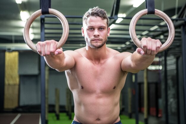 Retrato de hombre musculoso haciendo gimnasia de anillo