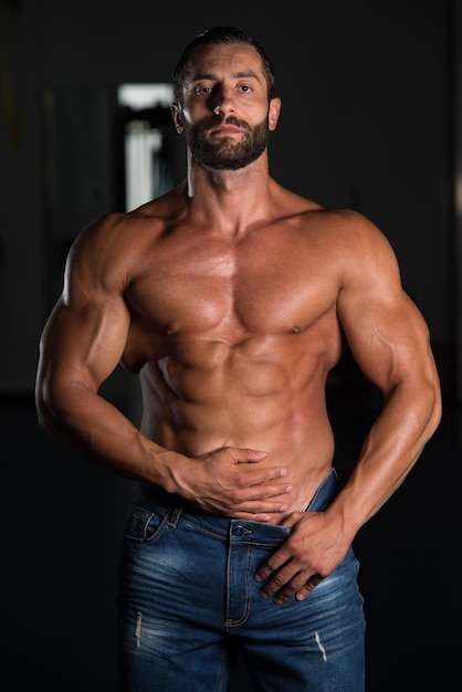 Retrato de un hombre musculoso sexy en pantalones posando después del ejercicio en el gimnasio