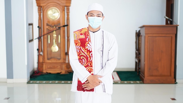 Un retrato de un hombre musulmán asiático con estilo en la mezquita, después de sholat, con máscara