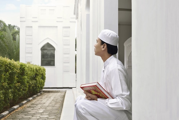 Retrato del hombre musulmán asiático que sostiene quran