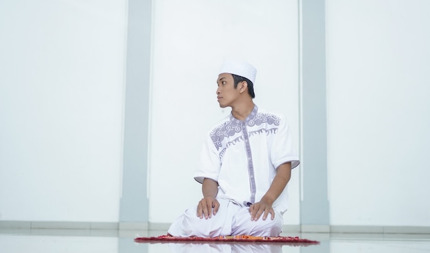 Foto un retrato de un hombre musulmán asiático reza en la mezquita, el nombre de la oración es sholat, se refiere al final de sholat