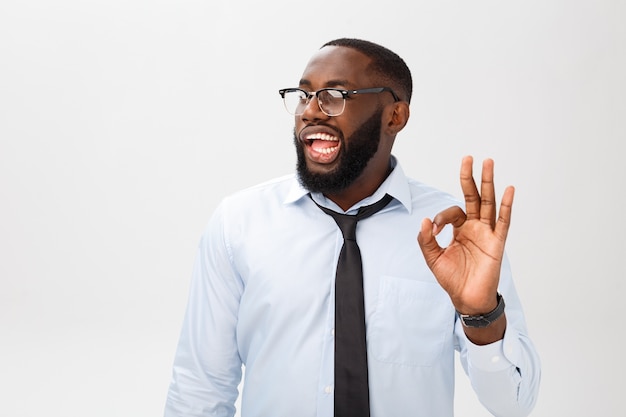 Retrato de hombre de negocios afroamericano sonriendo y mostrando signo bien.