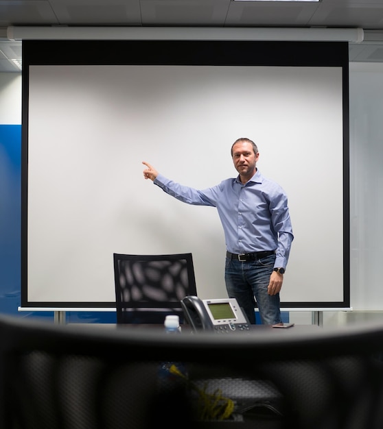 Foto retrato de un hombre de negocios apuntando a una pantalla de proyección en la oficina